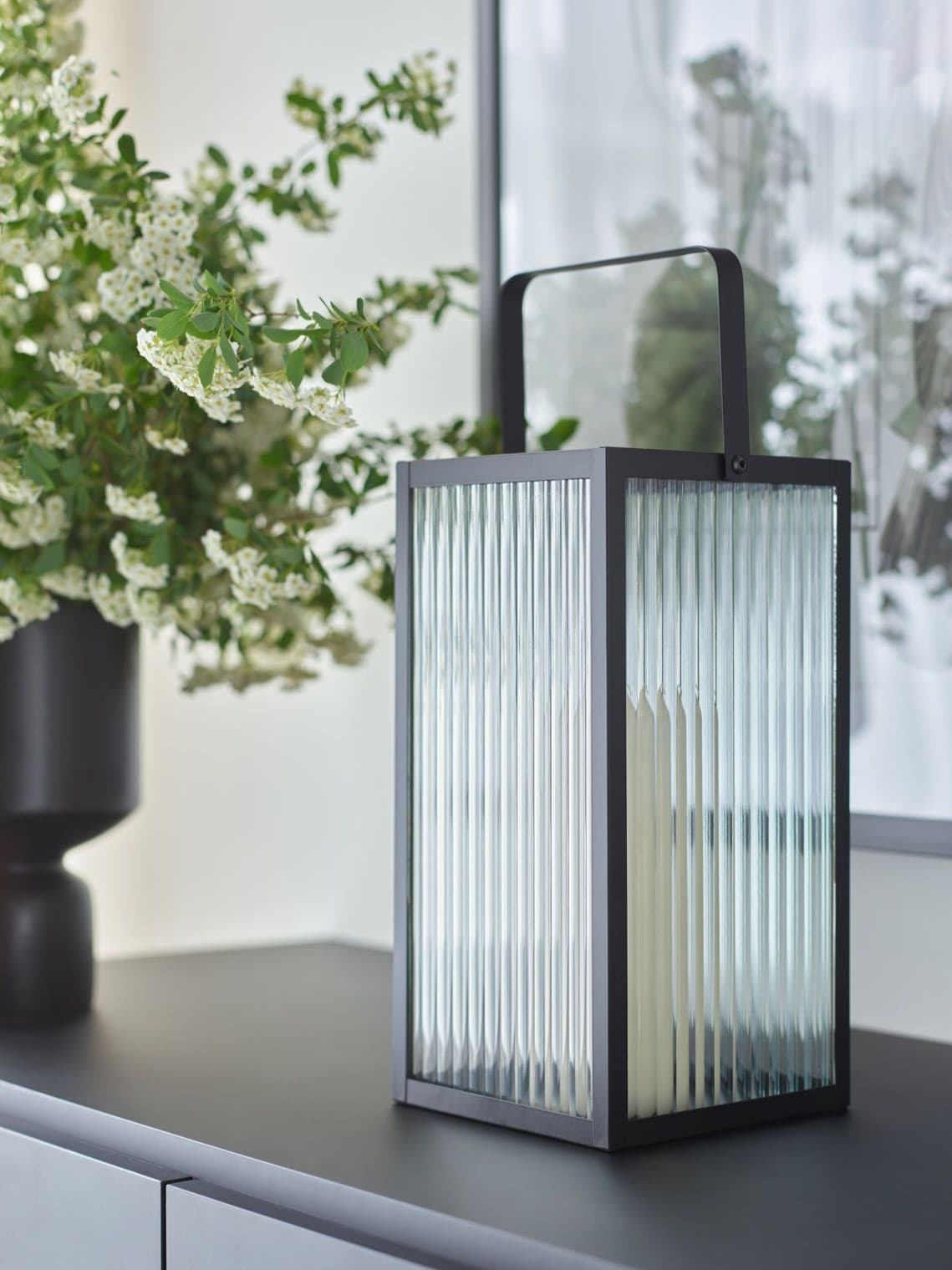 Lampion dekoracyjny z ryflwoanego szkła na komodzie